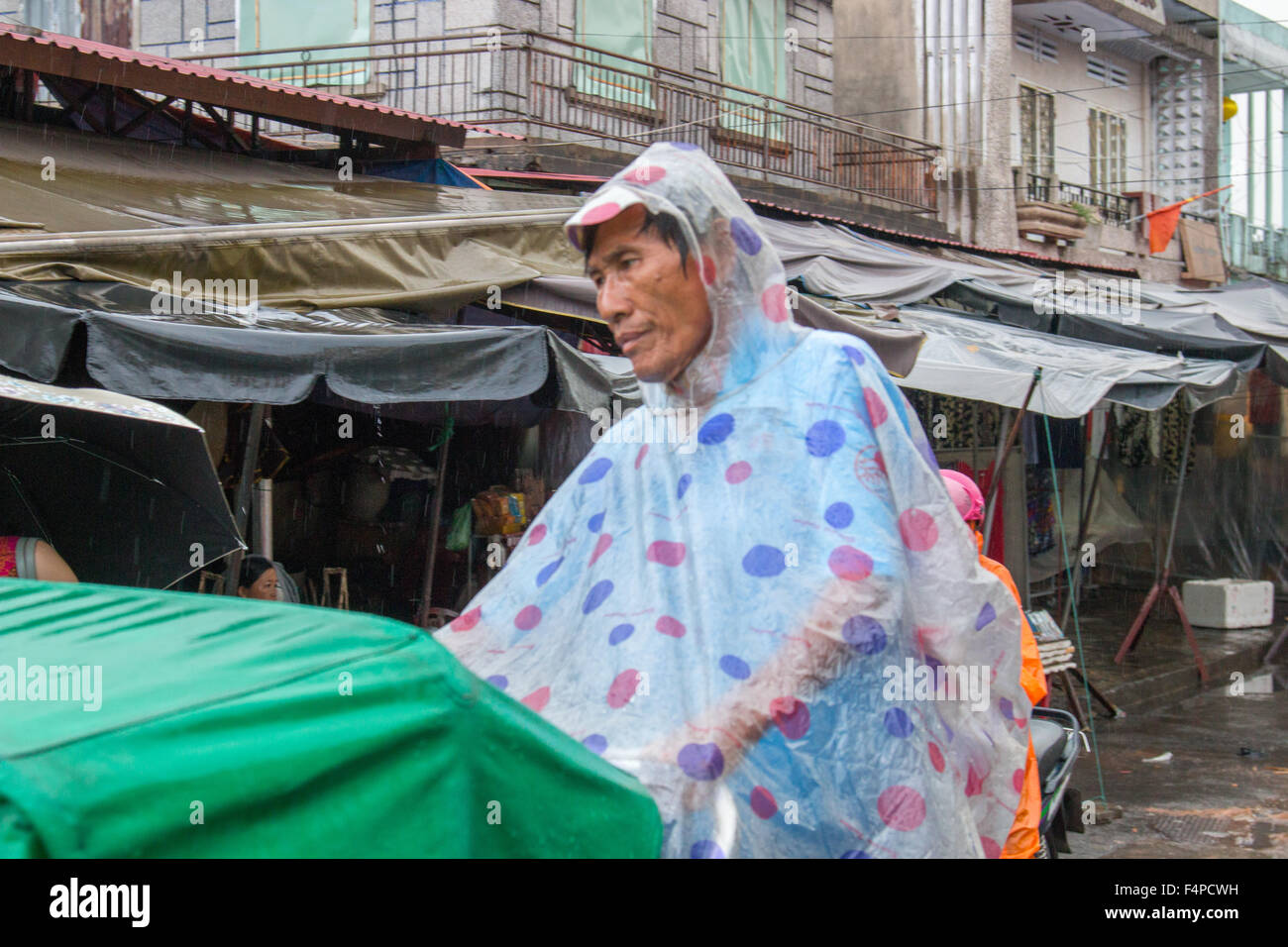 Hoi An ancient town Vietnam, cyclo rickshaw rider with waterproofs on to keep dry during rainstorm,Vietnam Stock Photo