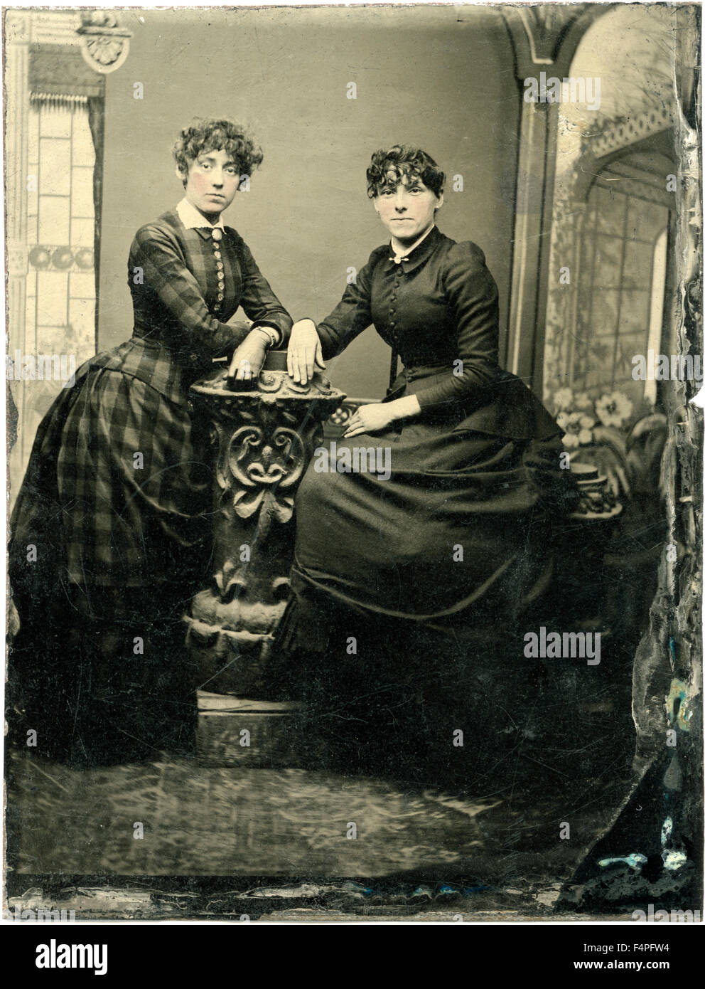 Portrait of Two Adult Women, One Seated, Both Leaning on Short Pillar, circa 1870 Stock Photo