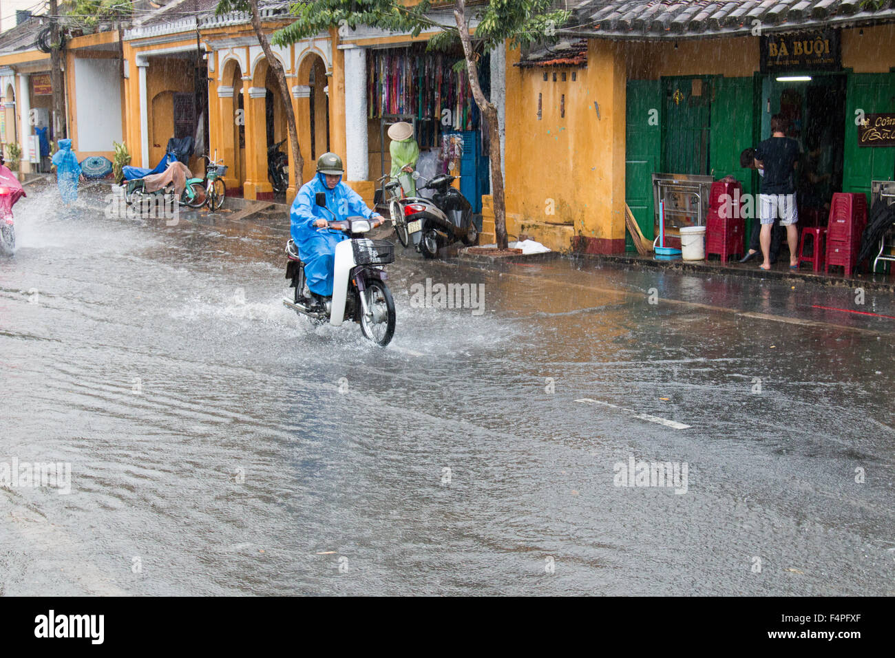 Hoi An ancient town Vietnam, biker on scooter motorcycle rides through flooded road during thunderstorms,Vietnam Stock Photo