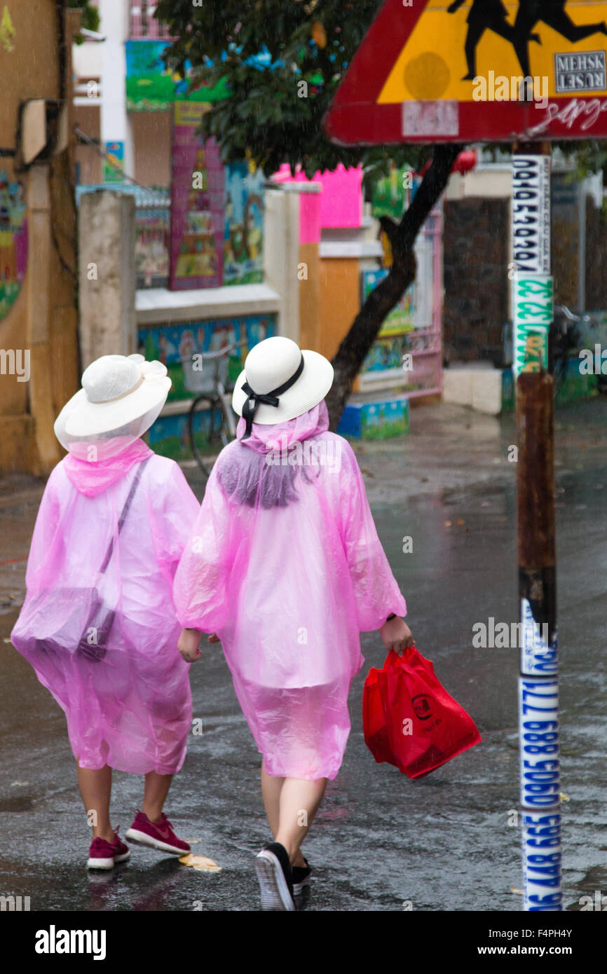 Hoi An ancient town Vietnam, two tourists wearing marching rainwear during a thunderstorm. Stock Photo