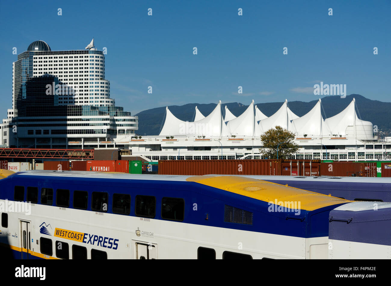 West Coast Express commuter train, freight cars and Canada Place sails, and Pan Pacific Hotel, Vancouver, BC, Canada Stock Photo