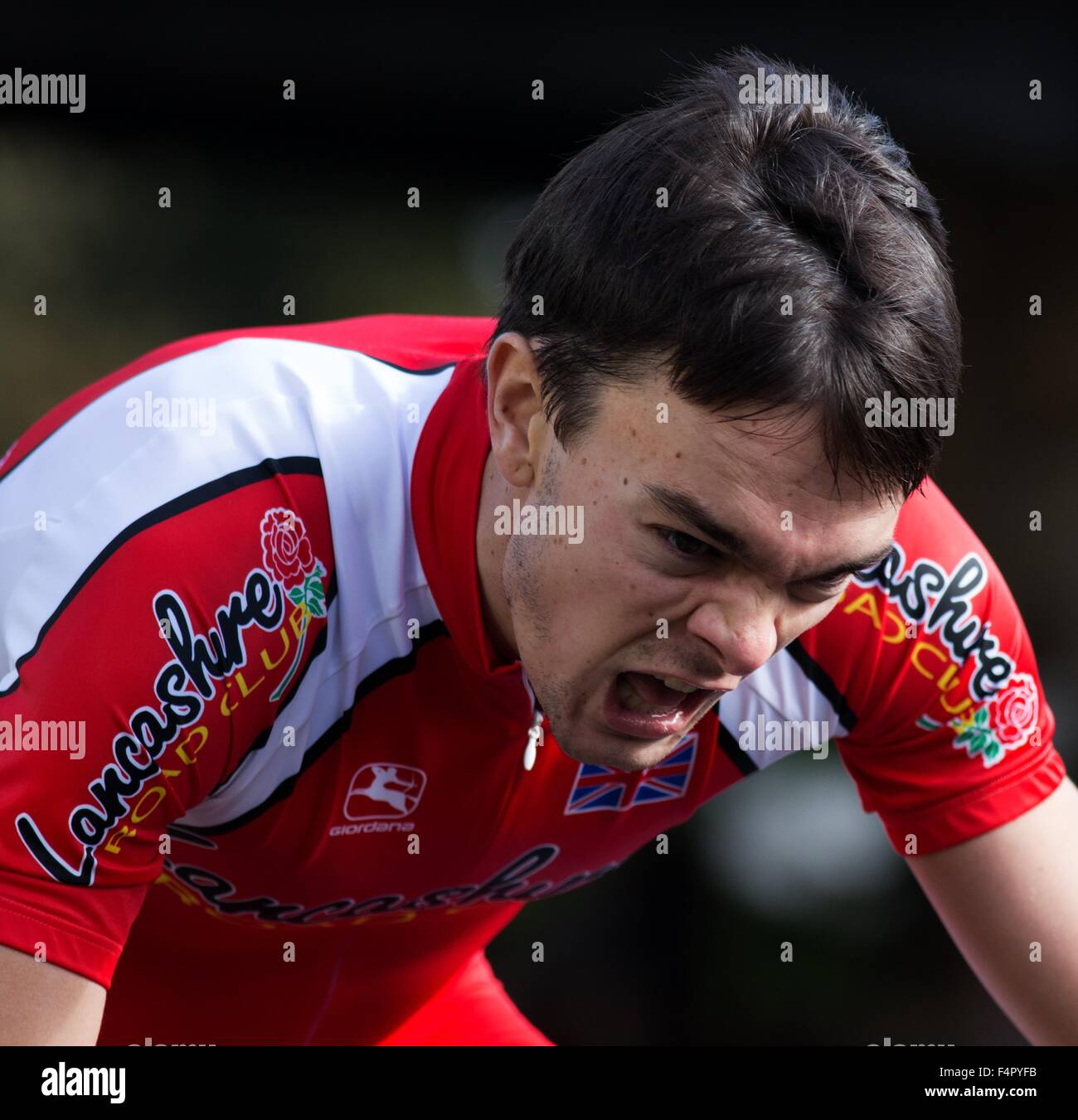Head and shoulders portrait of a cyclist in club colours trying very