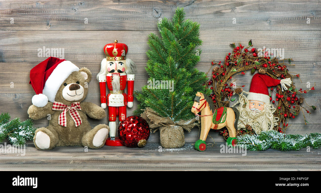 Nostalgic christmas decoration. Antique toys Teddy Bear in Santa Claus red hat and Nutcracker. Stock Photo