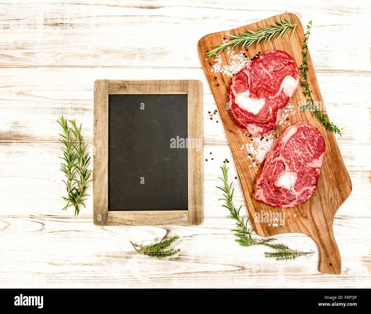 Raw fresh meat with herbs, spices and blackboard on wooden desk. Food background Stock Photo