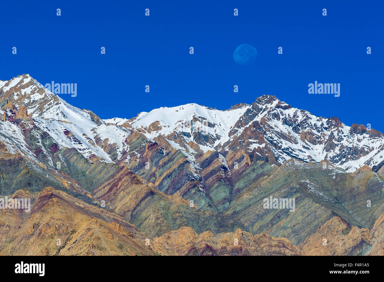 Snow covered, colorful  mountains with the rising moon above Stock Photo