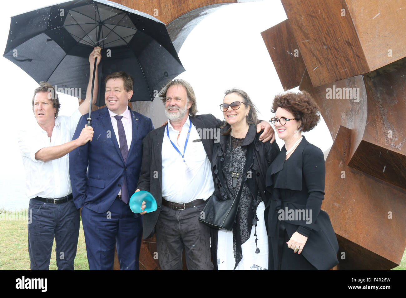 Sydney, Australia. 22 October 2015.  Pictured: Jorg Plickat (centre) from Germany next to his work ‘Divided Planet’ in the rain. He was announced as the winner of the $60,000 Macquarie Group Sculpture Prize. With, L-R: Founding Director David Handley, Troy Grant MP, Deputy Premier of New South Wales, his wife? An a representative from Macquarie Bank. 107 different sculptures can be seen at the 19th annual Sculpture by the Sea Bondi exhibition along the coastal walk between Bondi and Tamarama Beaches. Credit: Richard Milnes/Alamy Live News Stock Photo