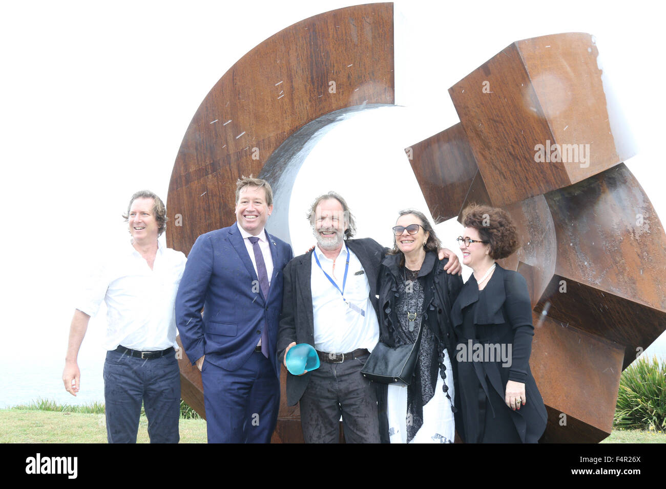 Sydney, Australia. 22 October 2015.  Pictured: Jorg Plickat (centre) from Germany next to his work ‘Divided Planet’ in the rain. He was announced as the winner of the $60,000 Macquarie Group Sculpture Prize. With, L-R: Founding Director David Handley, Troy Grant MP, Deputy Premier of New South Wales, his wife? An a representative from Macquarie Bank. 107 different sculptures can be seen at the 19th annual Sculpture by the Sea Bondi exhibition along the coastal walk between Bondi and Tamarama Beaches. Credit: Richard Milnes/Alamy Live News Stock Photo