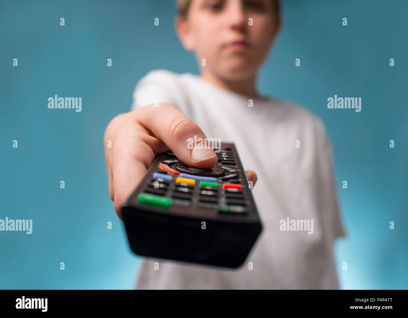 A bored boy changing channels using a TV remote control Stock Photo