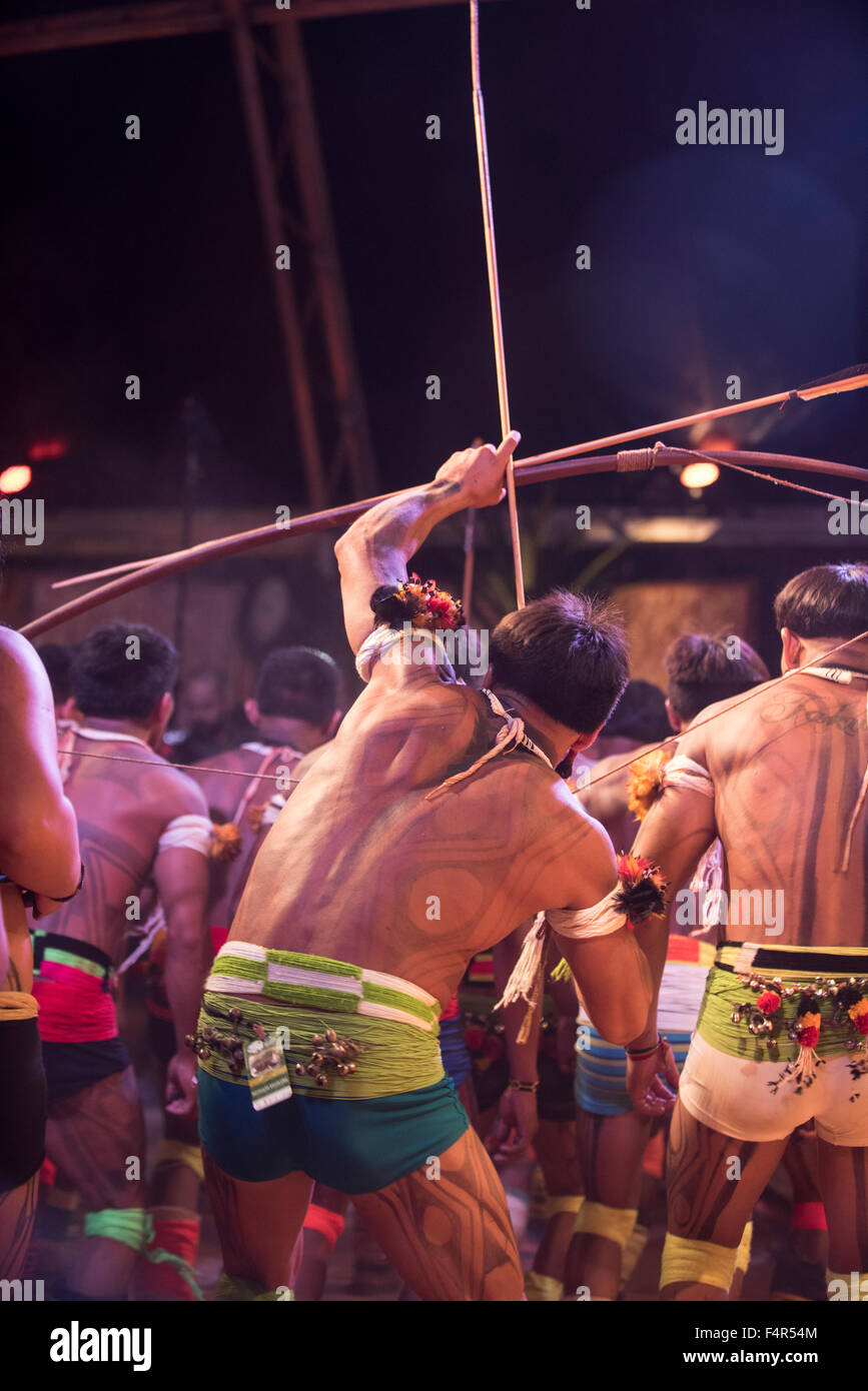 Palmas, Brazil. 21st Oct, 2015. Kuikuro warriors perform a war dance; one draws the string on his bow with an arrow notched at the first ever International Indigenous Games, in the city of Palmas, Tocantins State, Brazil. The games will start officially with an opening ceremony on Friday the 23rd October. Credit:  Sue Cunningham Photographic/Alamy Live News Stock Photo