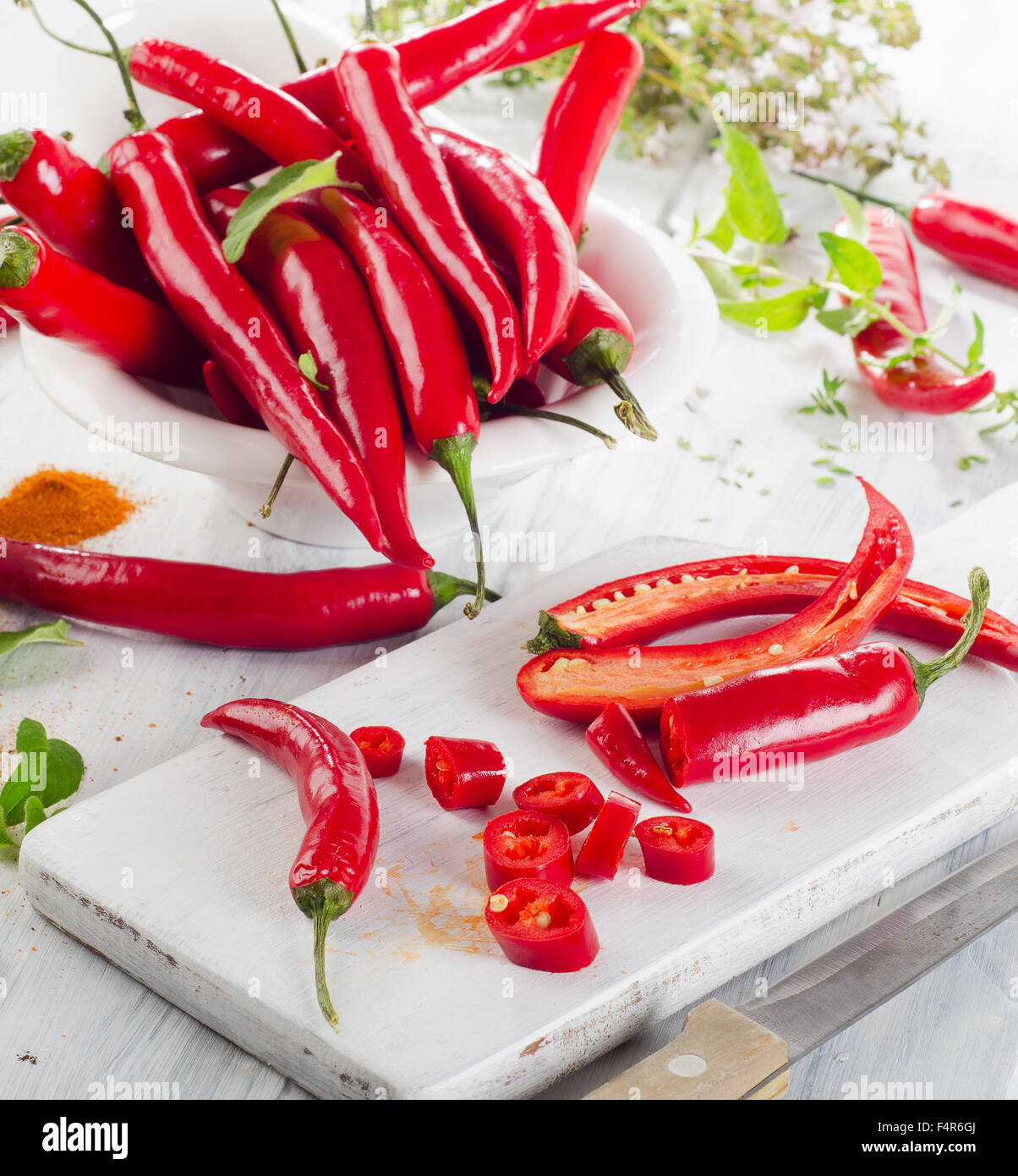 Red chili peppers with herbs leaves  in  a white bowl. Selective focus Stock Photo