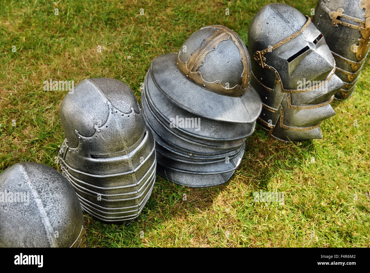 Helmets of knights stocked on green grass field Stock Photo