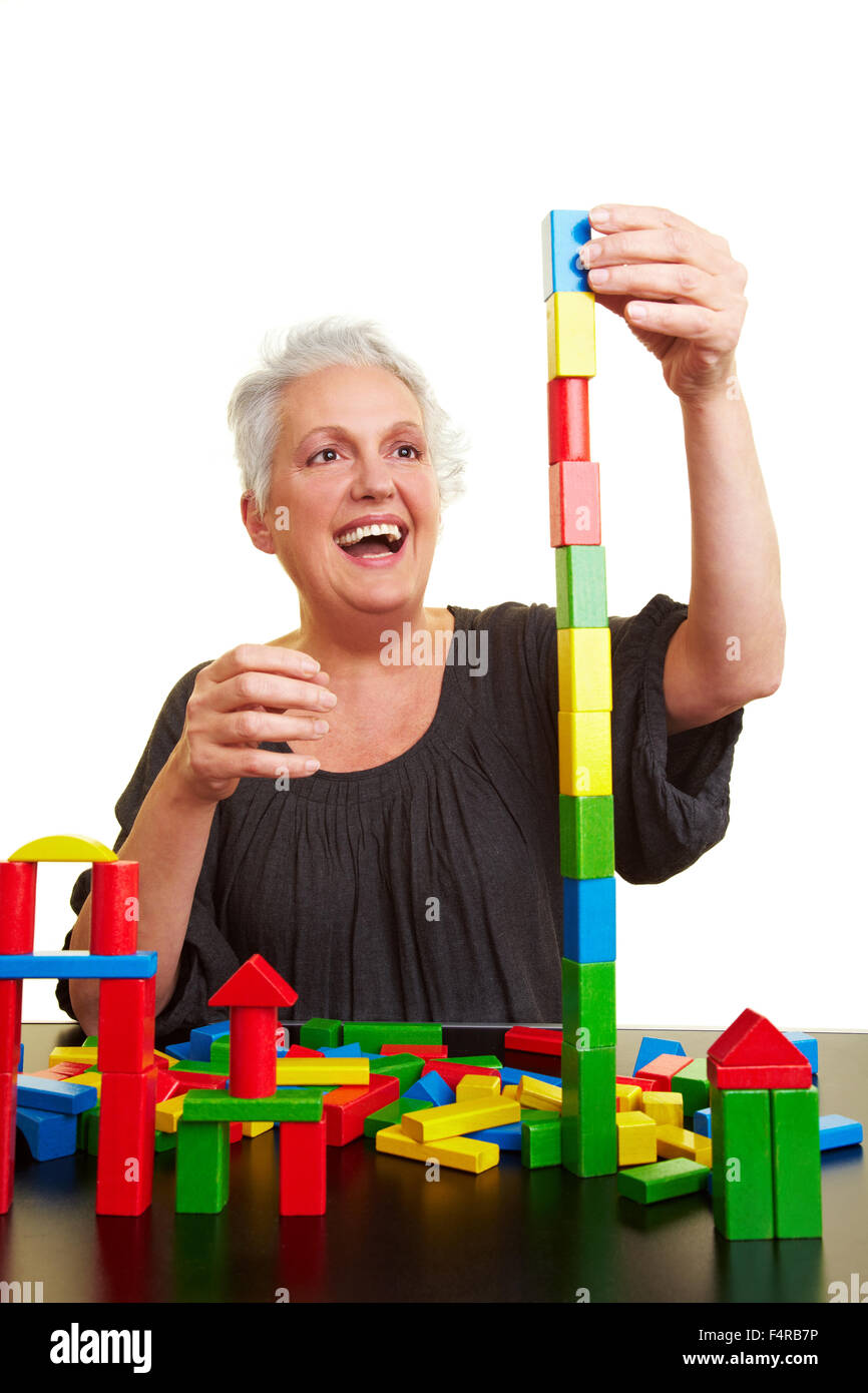 Happy senior woman with many colorful building blocks Stock Photo