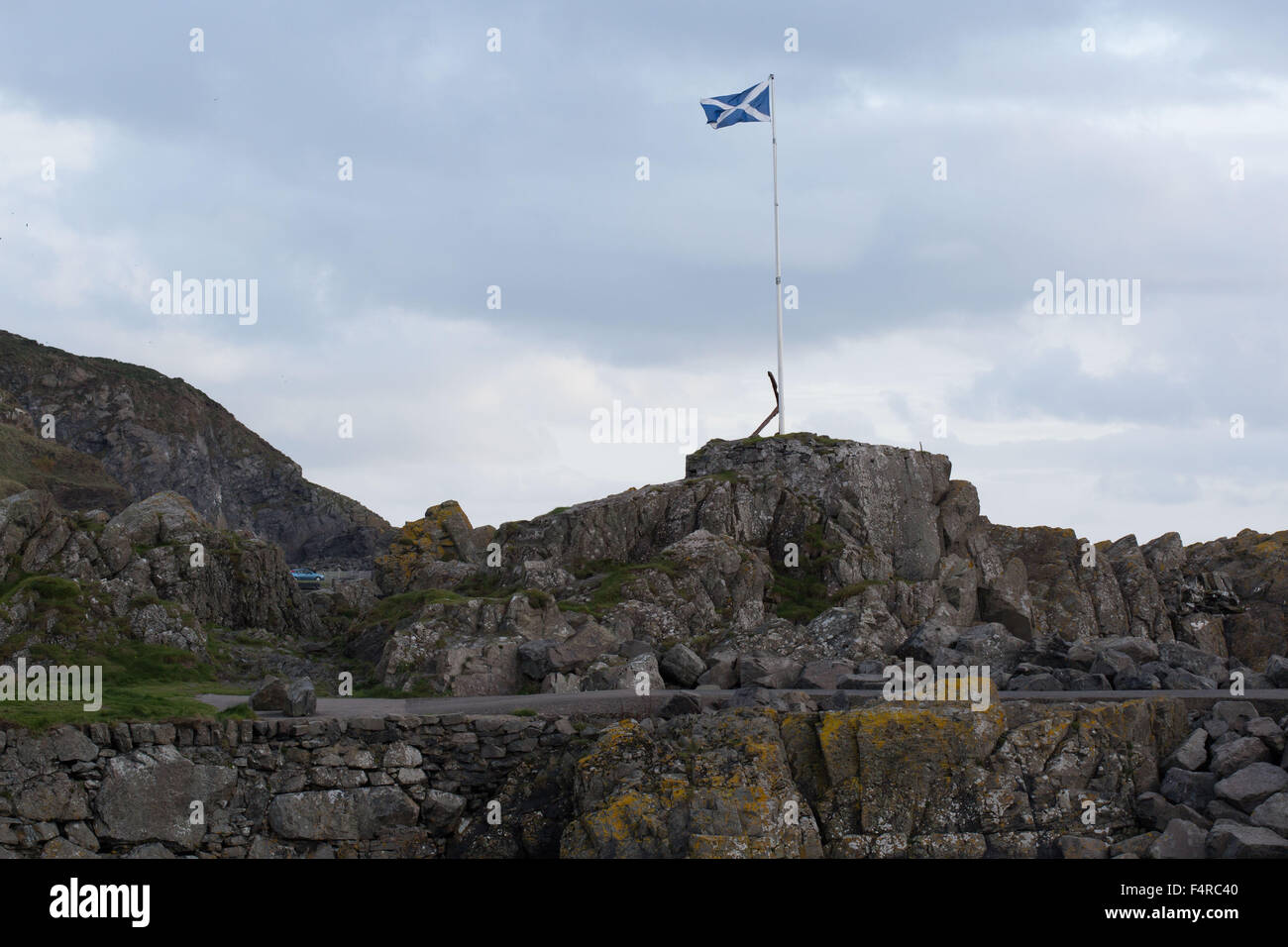 A Saltire flies before dramatic skies over the coastline at Portpatrick in Dumfries and Galloway, Scotland, Britain. Stock Photo