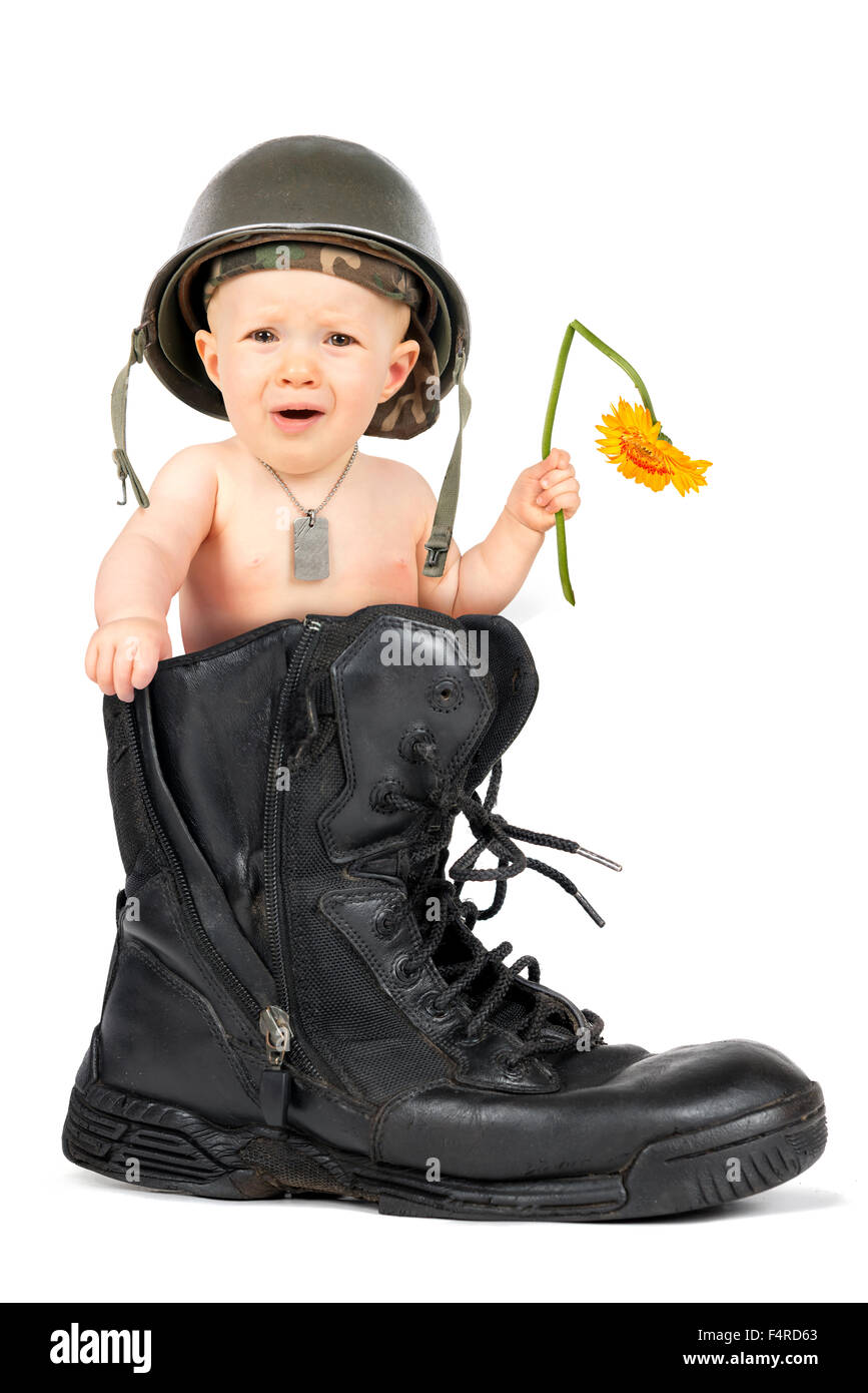 Cute baby girl soldier with flower inside a military boot Stock Photo