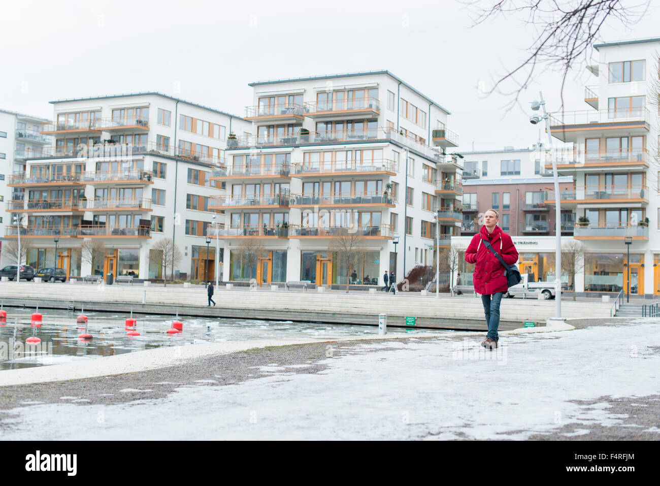 Sweden, Sodermanland, Stockholm, Hammarby Sjostad, Man walking in residential area in winter Stock Photo