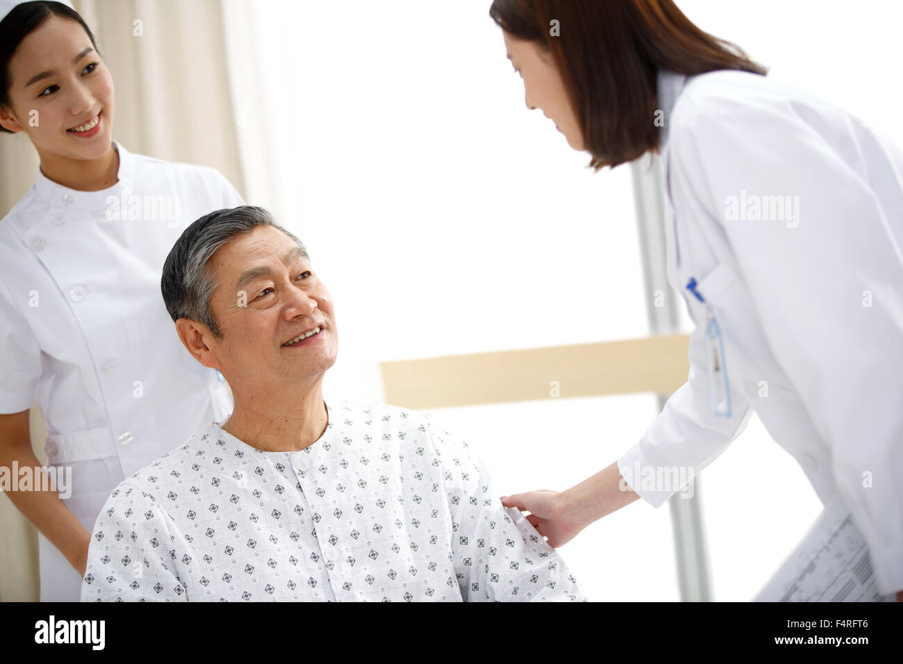 Medical workers greet old people sitting in a wheelchair. Stock Photo