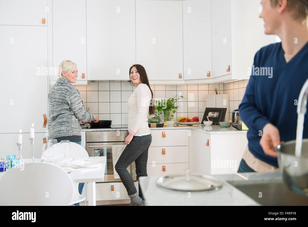Two women and man in domestic kitchen Stock Photo