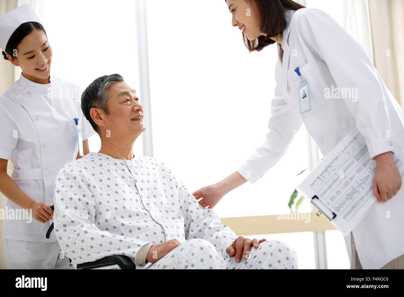 Medical workers greet old people sitting in a wheelchair. Stock Photo