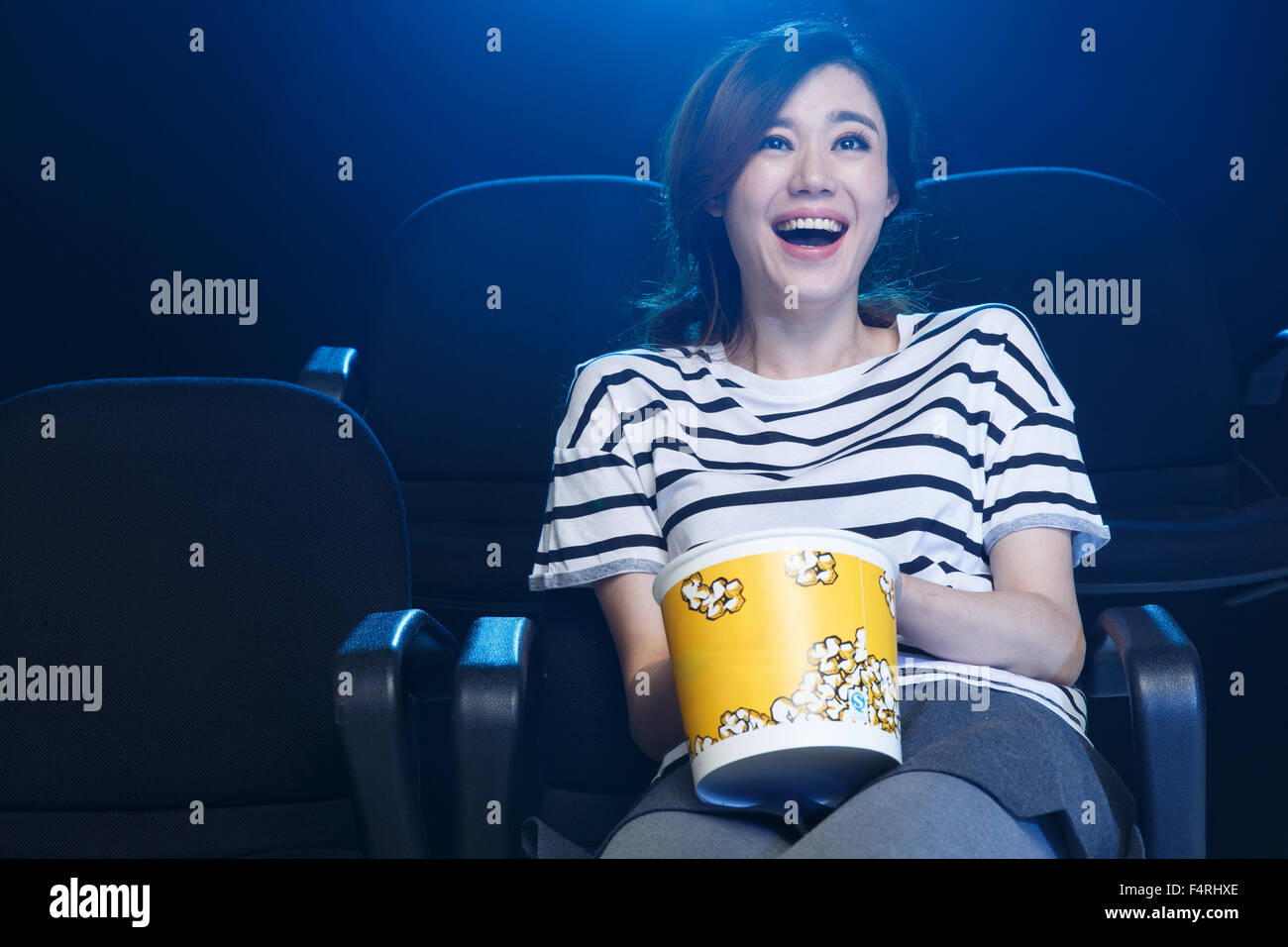 A young woman is watching a movie in the cinema. Stock Photo