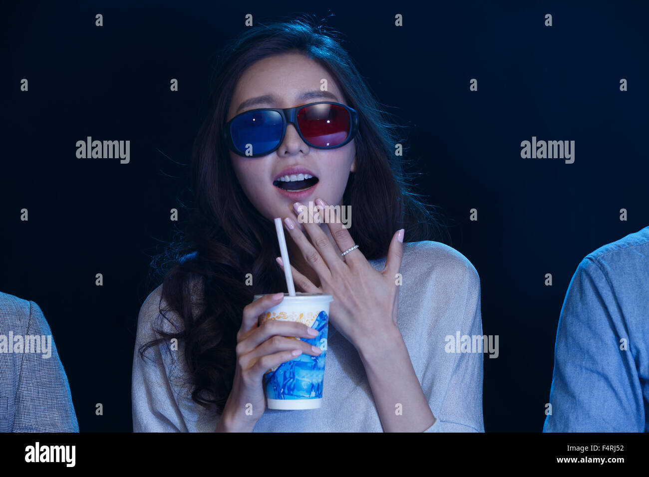 A young woman is watching a movie in the cinema. Stock Photo