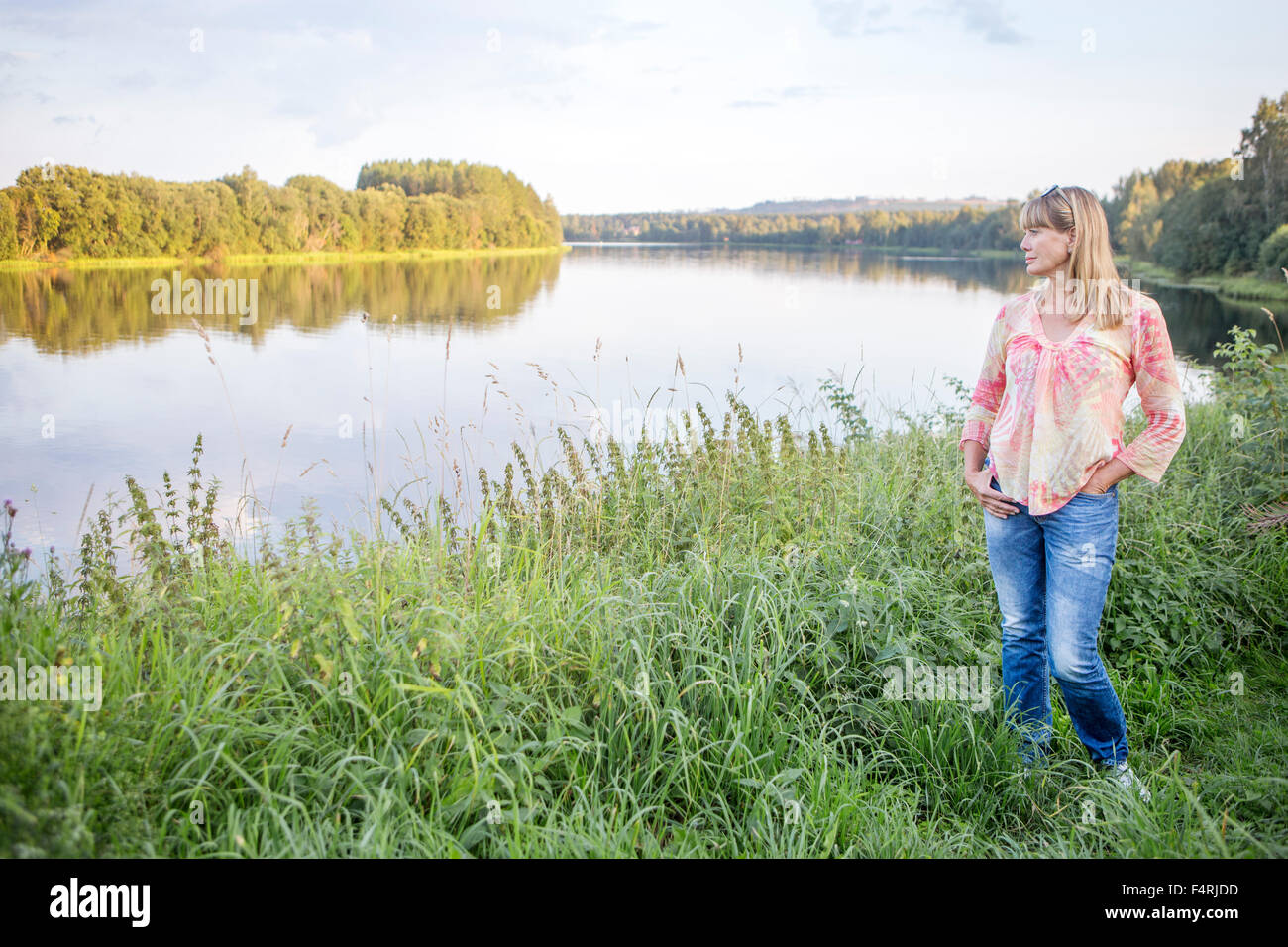Sweden, Dalarna, Borlange, Woman stinging on grassy riverbank Stock