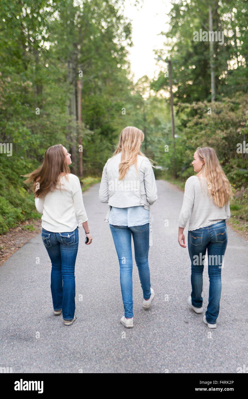 Sweden, Sodermanland, Nacka, Girls (14-15) walking road in forest Stock Photo