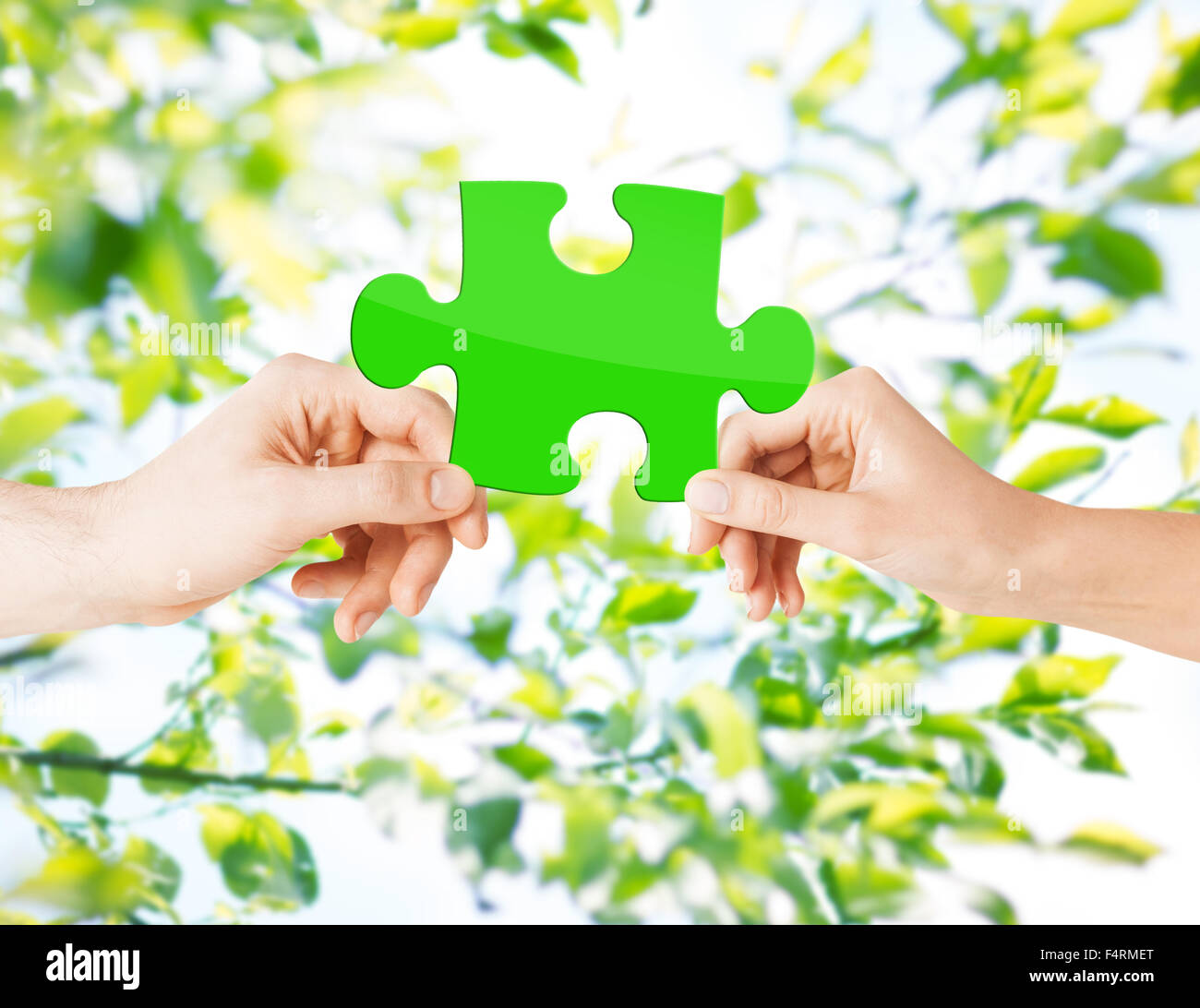hands with green puzzle over natural background Stock Photo