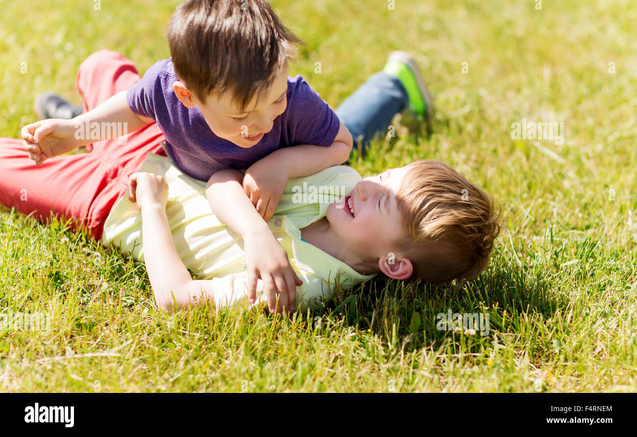 happy little boys fighting for fun on grass Stock Photo