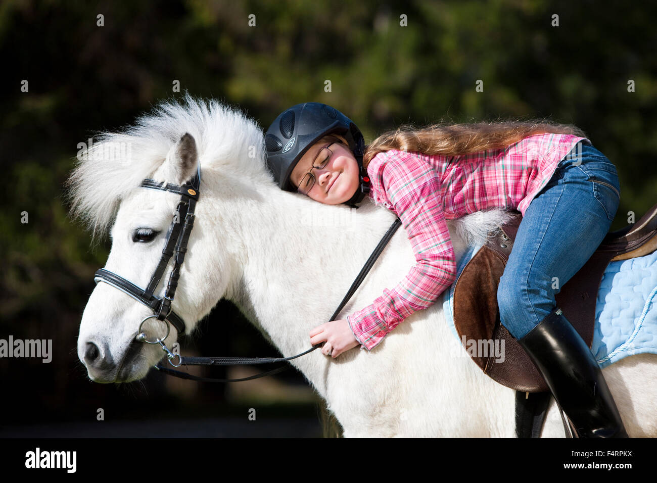 Happy girl sitting on a pony and cuddling, Schimmel, Austria Stock Photo