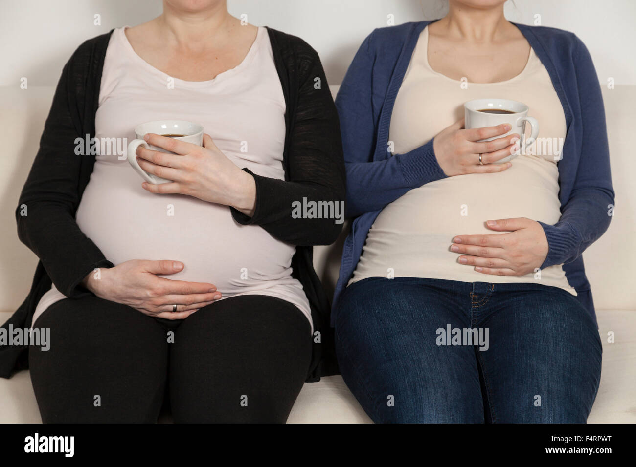 tow pregnant women sitting on sofa with coffee Stock Photo