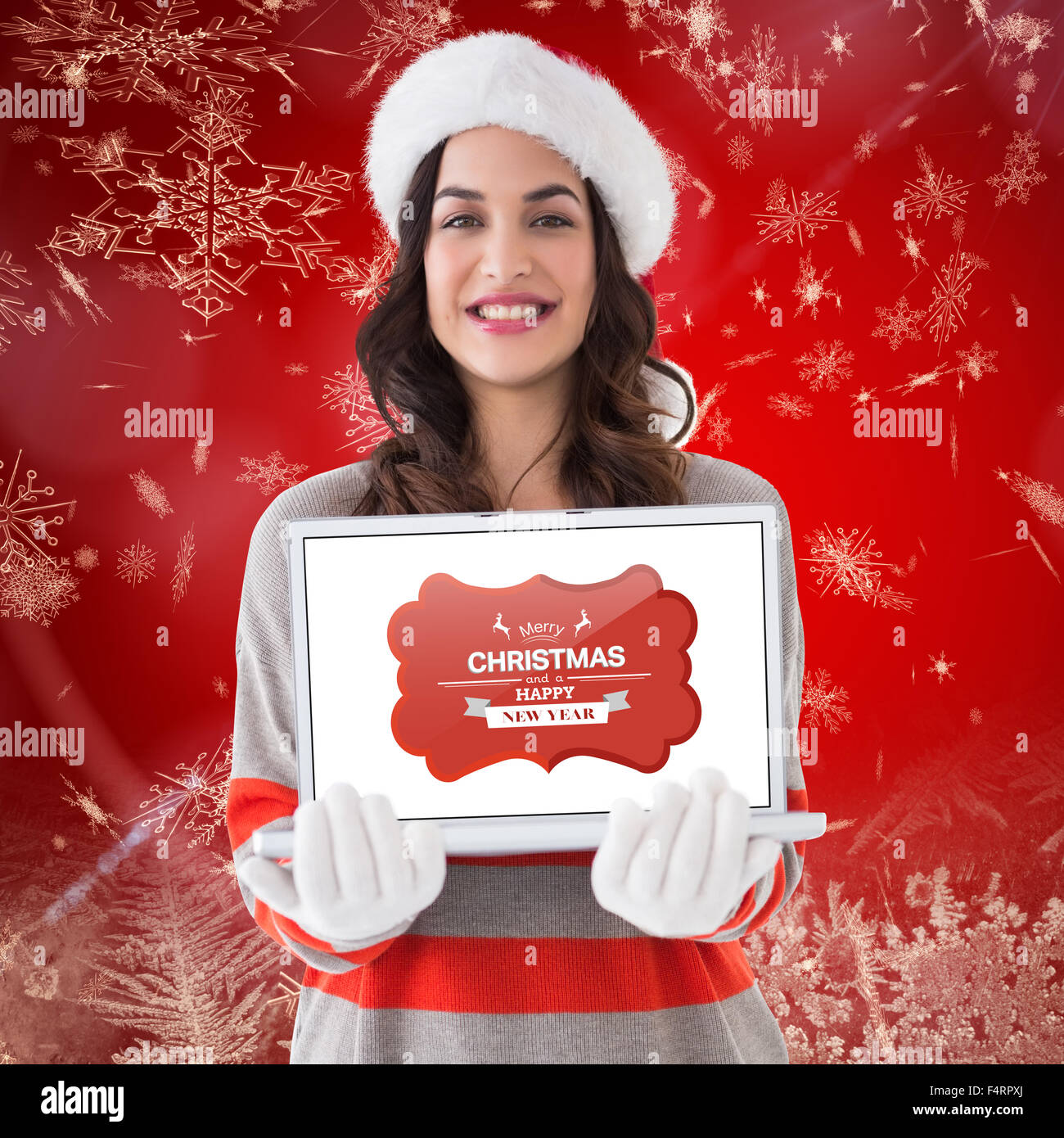 Composite image of festive brunette showing a laptop Stock Photo