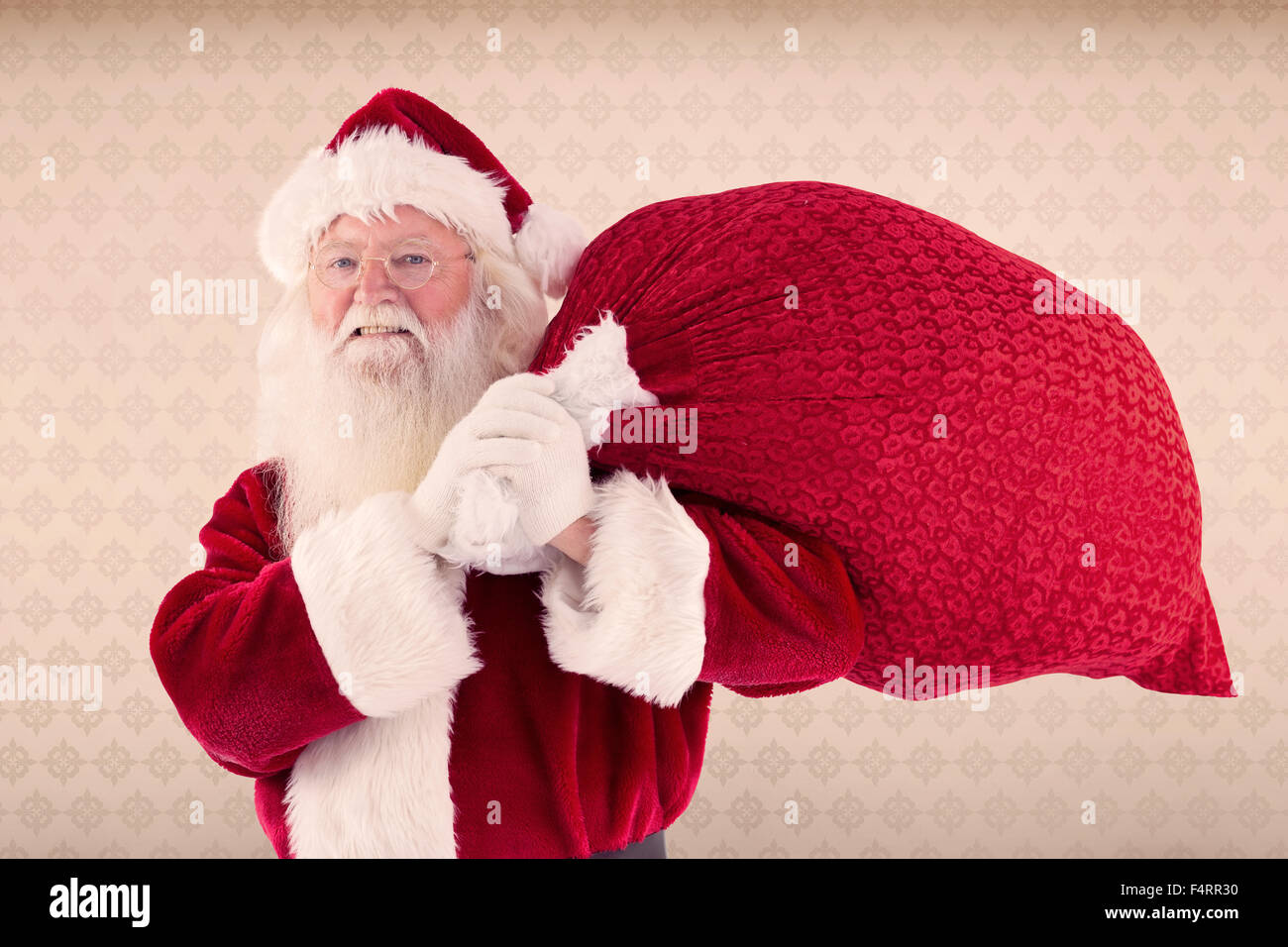 Composite image of santa carries his red bag and smiles Stock Photo - Alamy