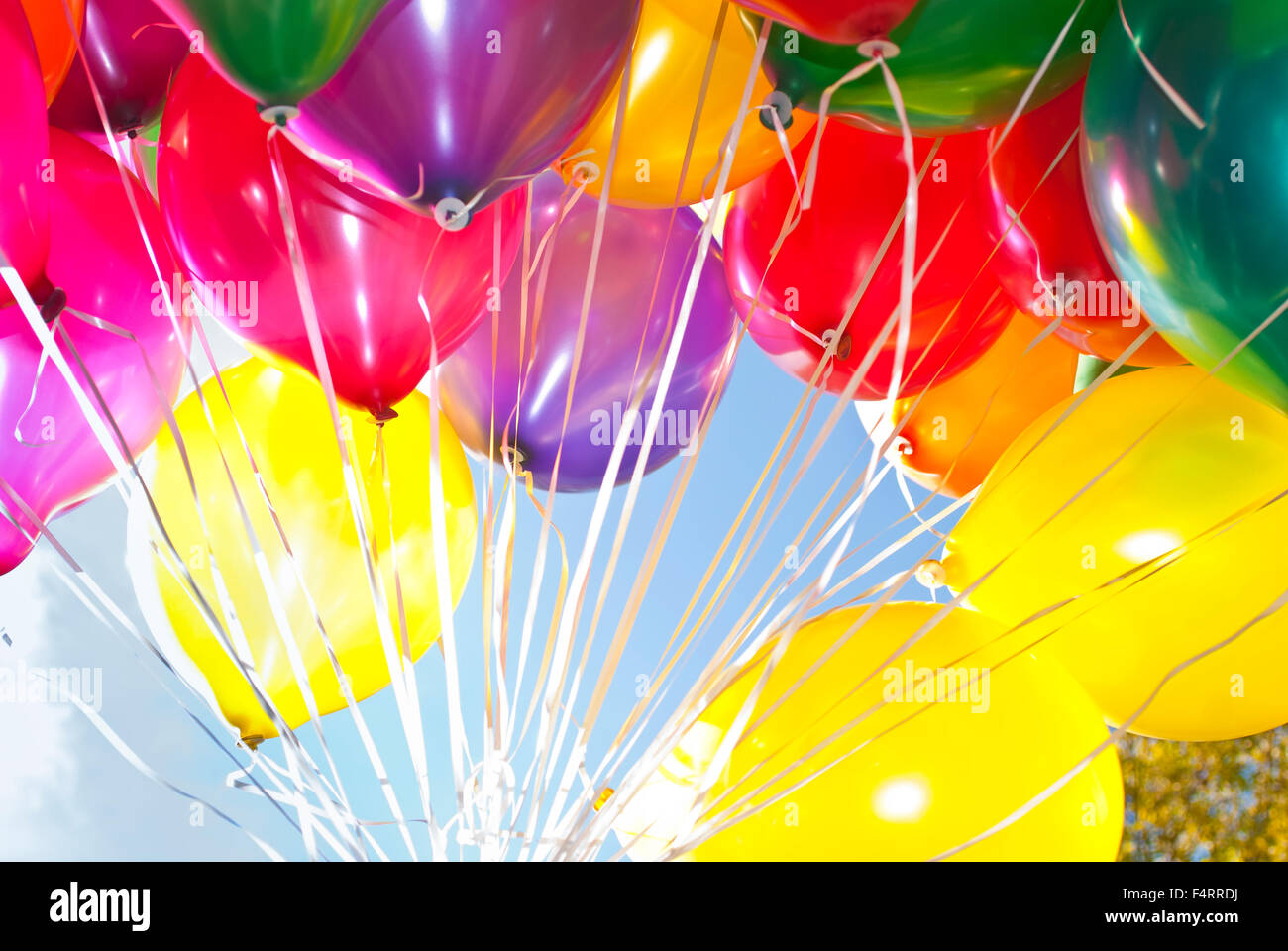 Colourful helium-filled balloons against a blue sky Stock Photo