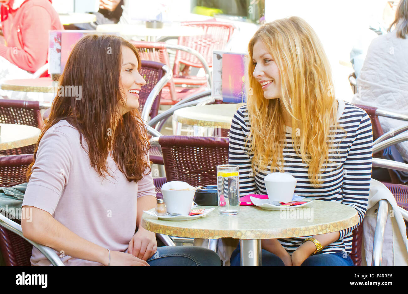Two girls have a talk in a street cafe Stock Photo