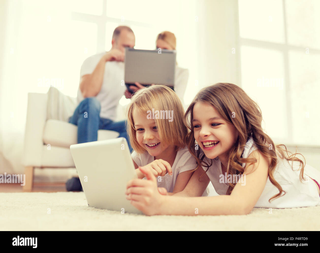 smiling sister with tablet pc and parents on back Stock Photo