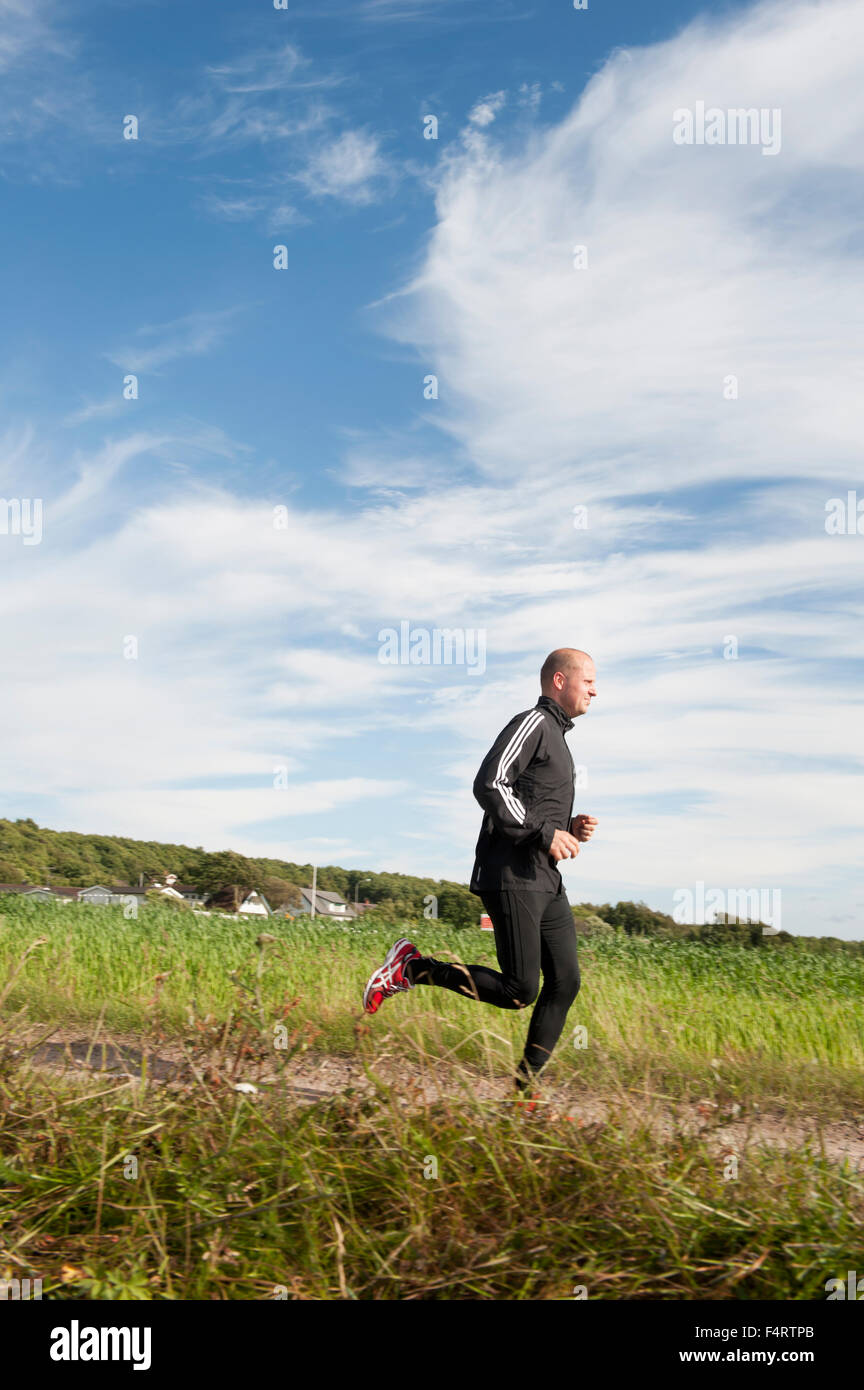 Sweden, Halland, Steninge, Mid-adult man running in field Stock Photo