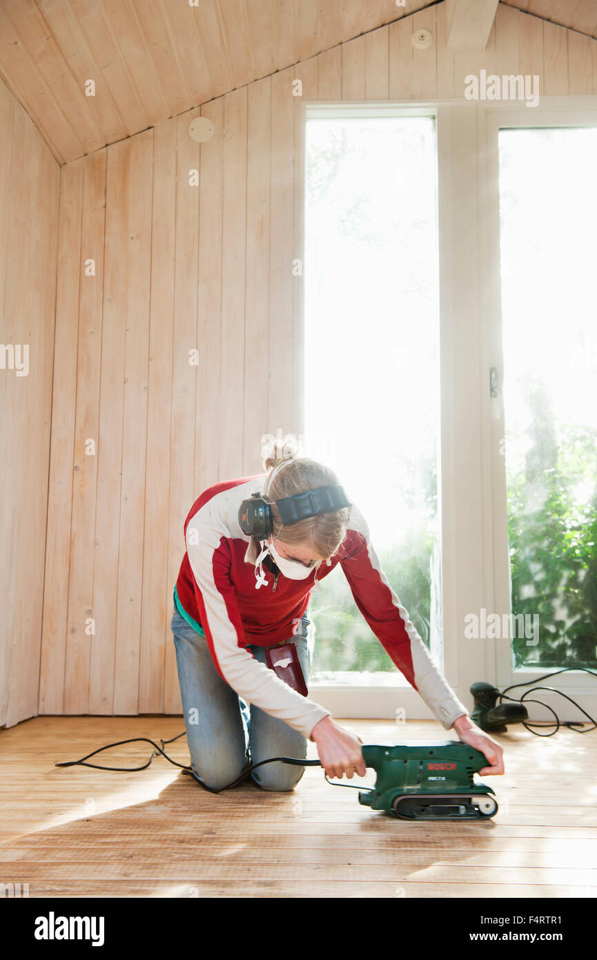 Woman sanding hardwood floor Stock Photo