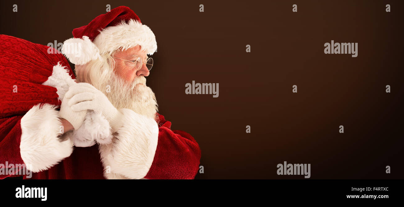 Composite image of santa claus carrying sack Stock Photo - Alamy