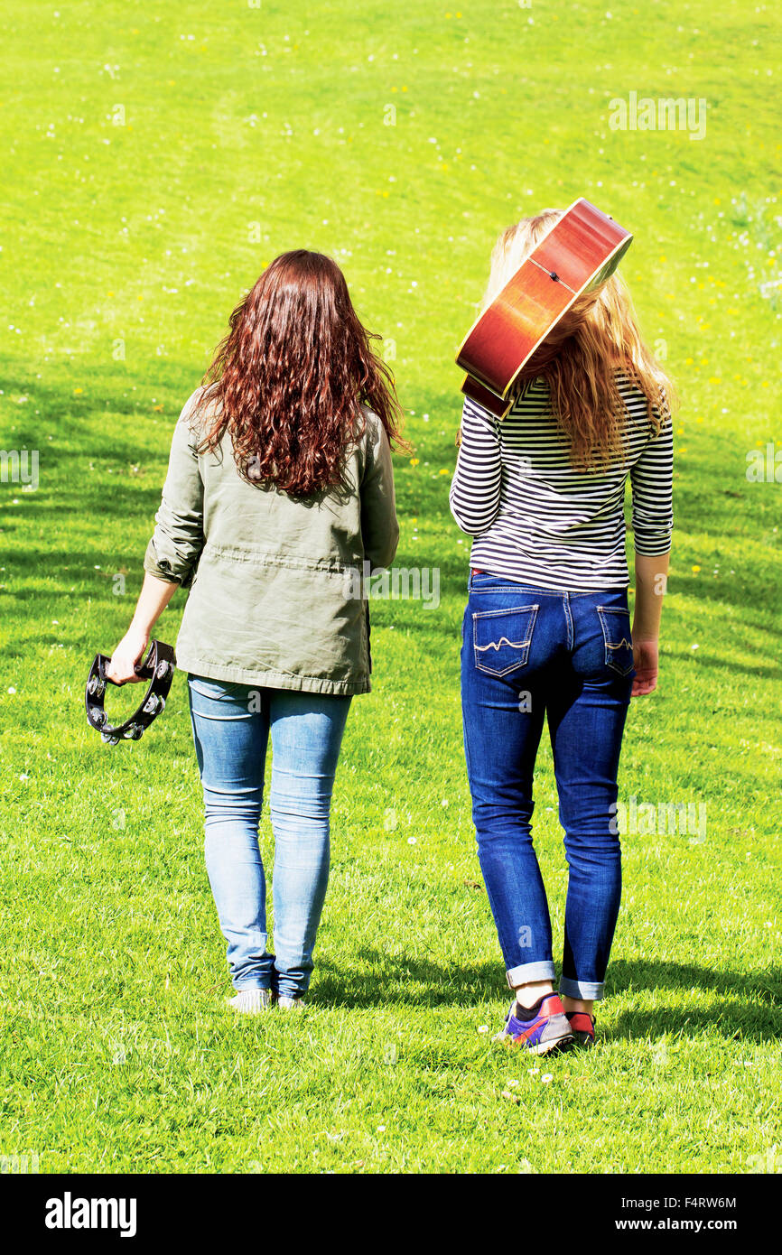 Two girls walking on a meadow with their instruments Stock Photo