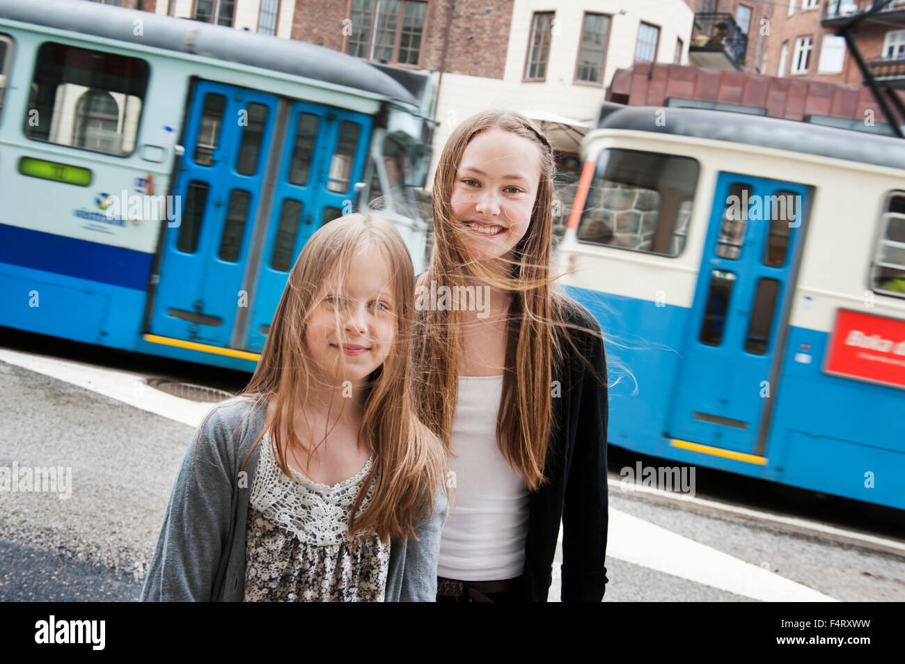 Portrait of girls (8-9, 14-15) posing in front of tram Stock Photo