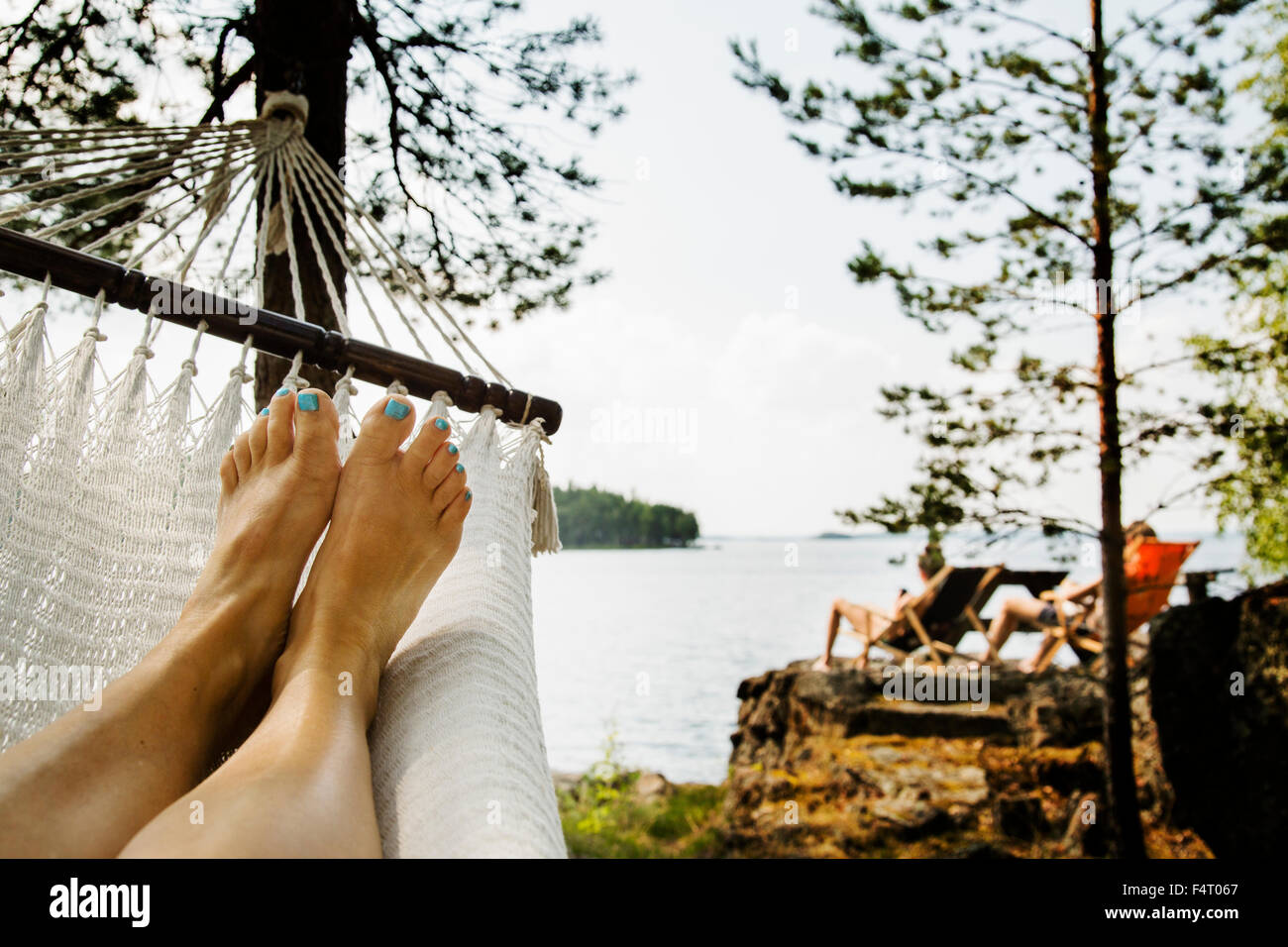 Sweden, Dalarna, near Falun, Lake Runn, Young woman relaxing in hammock