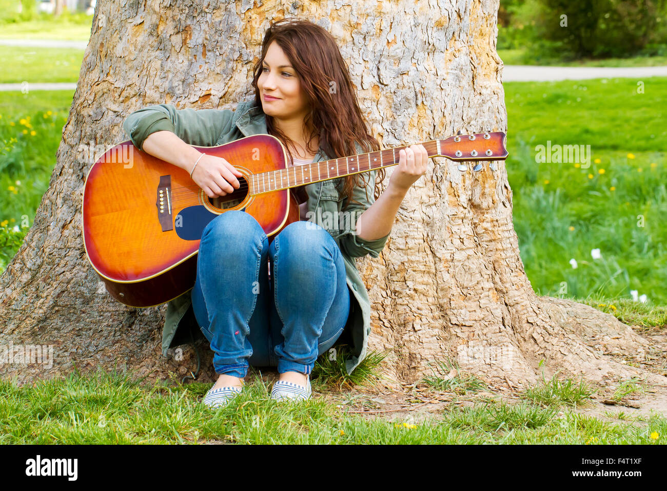 Girl with guitar sitting on a tree Stock Photo