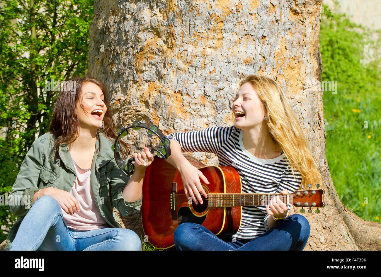 Two girls sitting in the park and making music Stock Photo