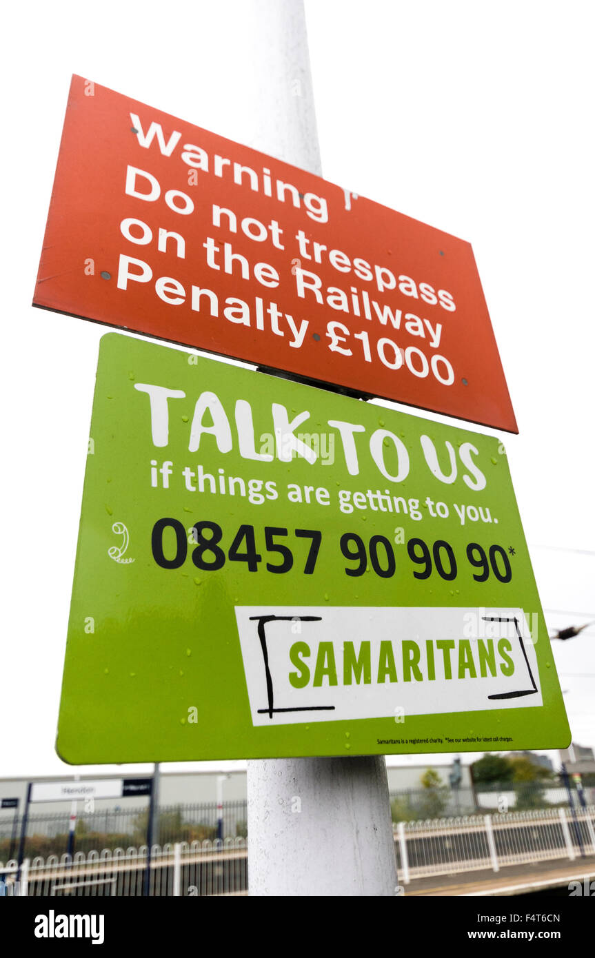 Signs at a railway platform in London warning not to trespass on the railway with a penalty of £1000, also an anti-suicide sign Stock Photo