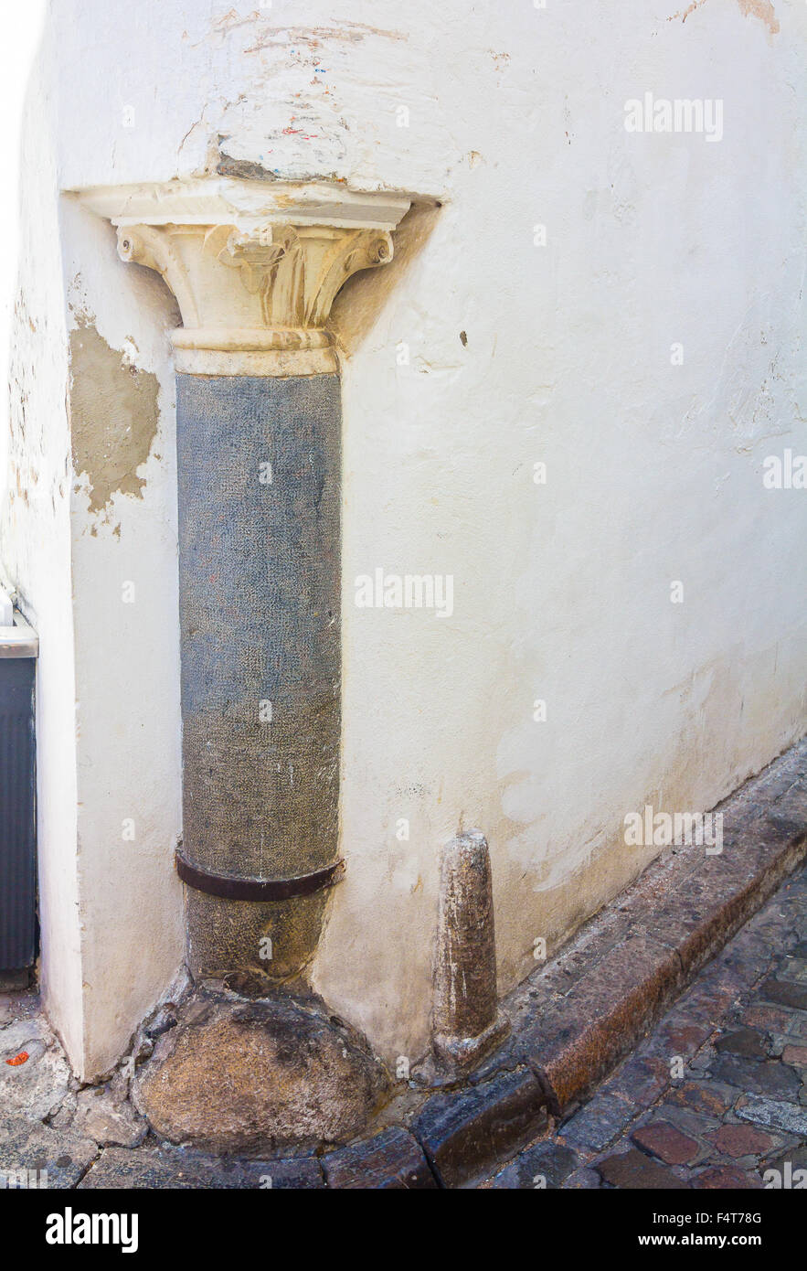 ancient granite column tucked in the corner of a house Stock Photo