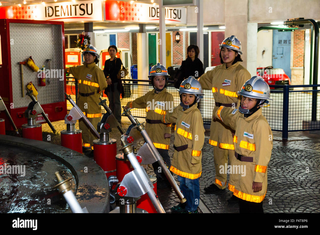 Japan, Nishinomiya, KidZania, children's role playing activity centre. Interior. Children dressed as firemen sounding the all clear after a fire. Stock Photo