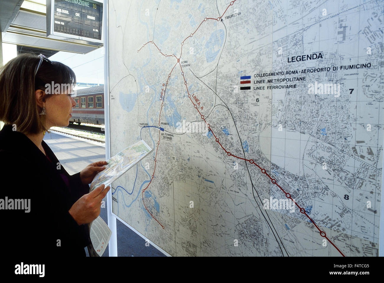 A young female looking a train map at a railway station near Rome. Italy . Europe Stock Photo