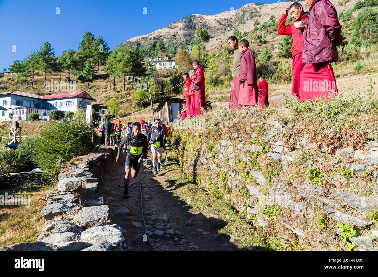 Monks wearing red cloths watching the start of the Solo Khumbu Trail race Stock Photo