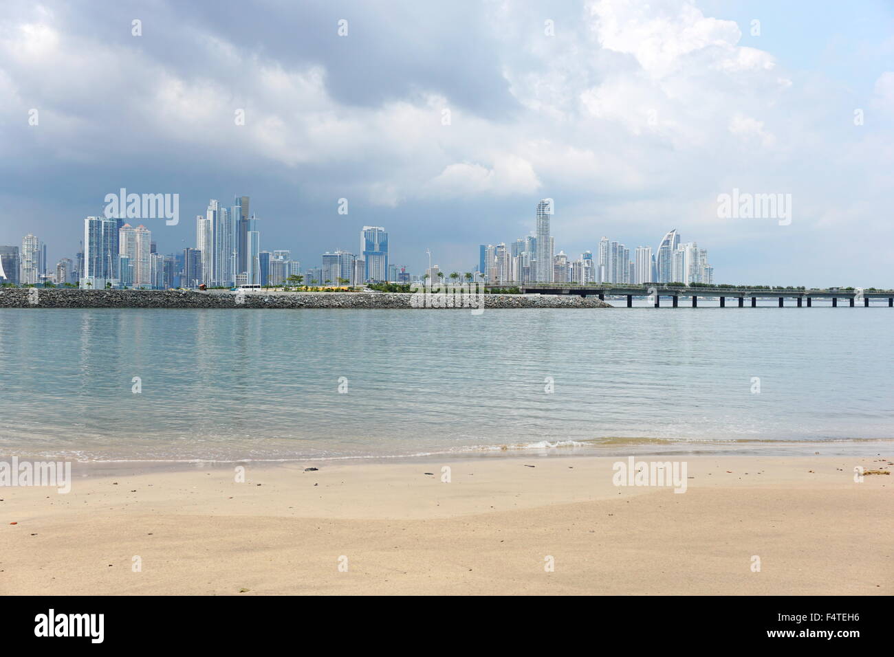 Beach sand in foreground with the new highway over the bay and Panama city skyscrapers in background, Panama, Central America Stock Photo