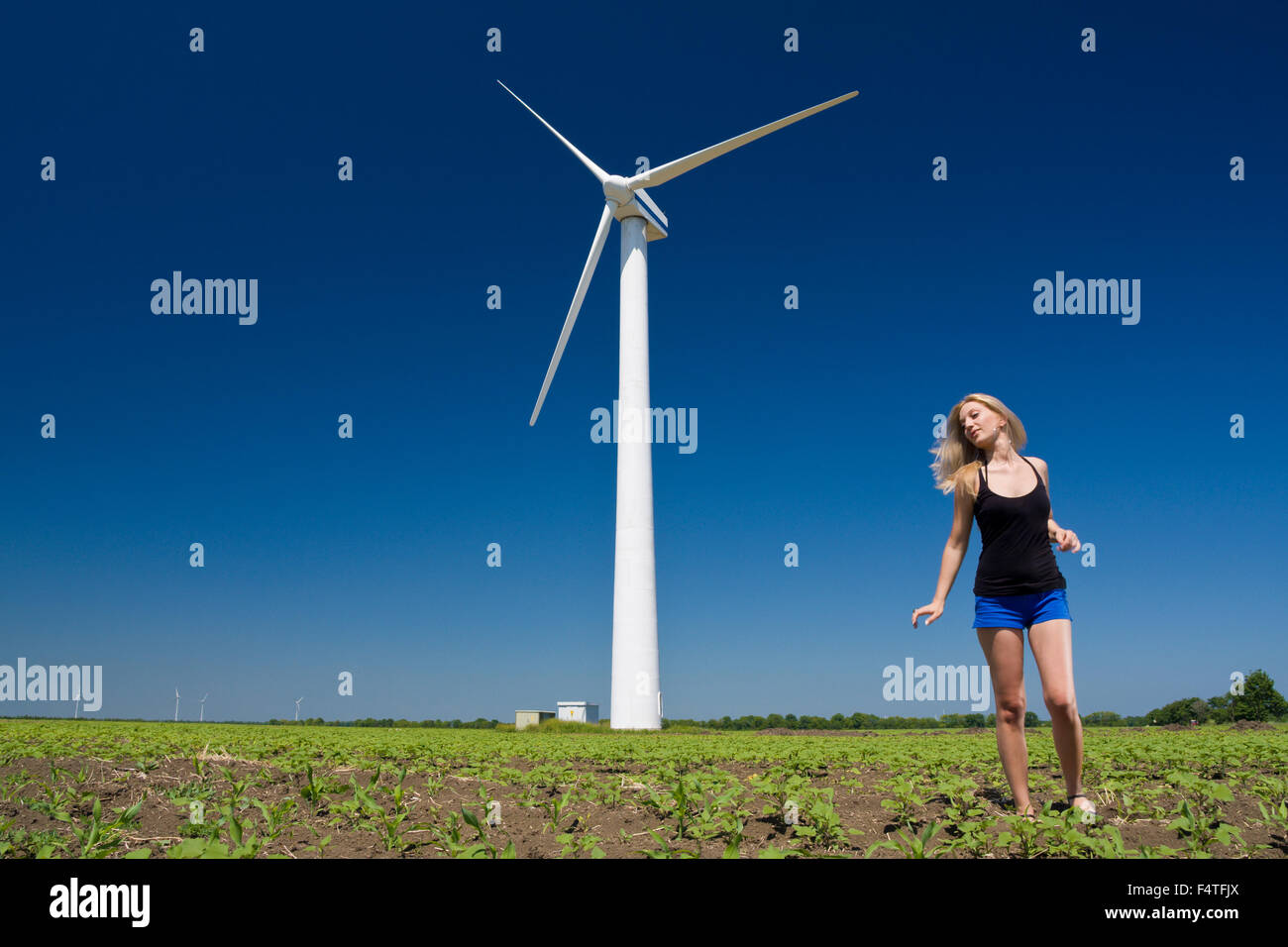 Female at wind power generator turbine - alternative and green energy source Stock Photo
